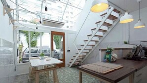A modern kitchen with a staircase, a dining area, and a view of parked cars outside. - TWH Hostel Bangkok (Bangkok)