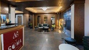 Eine moderne Hotelhalle mit einer Rezeption, einer Sitzecke und großen Fenstern.