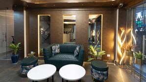 Eine moderne Lobby mit einem grünen Sofa, zwei runden Tischen und Topfpflanzen.