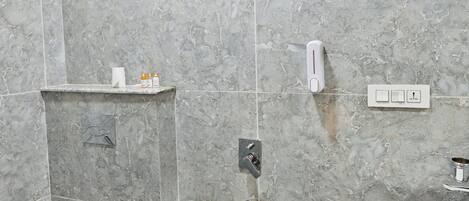 A bathroom with a toilet, bidet, shower, and sink.