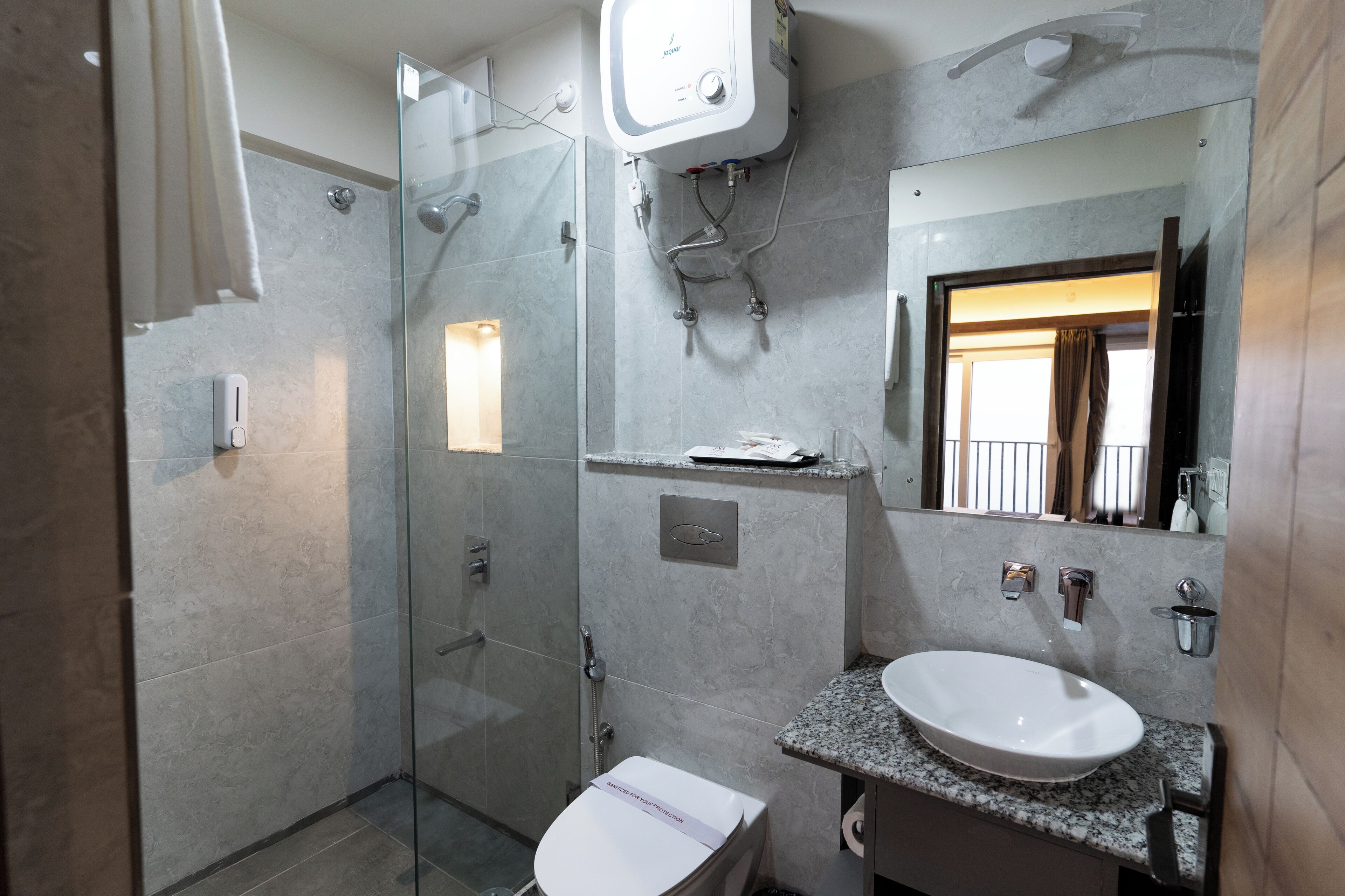 Un baño con cabina de ducha de vidrio, un lavabo blanco y un espejo sobre él.