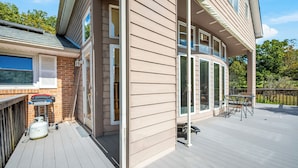Une maison avec une terrasse, un barbecue et une bouteille de propane.
