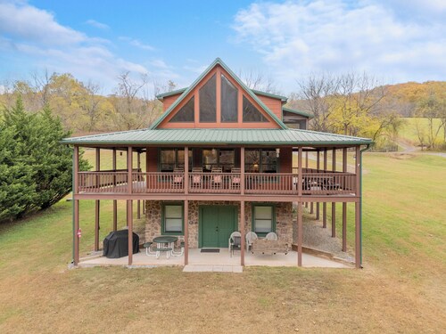 Sunny riverside cabin with loft views, big deck, game room, porches, and open lawn.