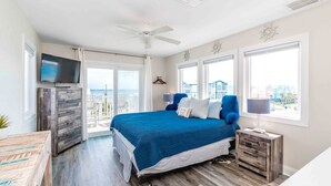 Un dormitorio con cama, televisión, ventilador de techo y vistas de la ciudad.
