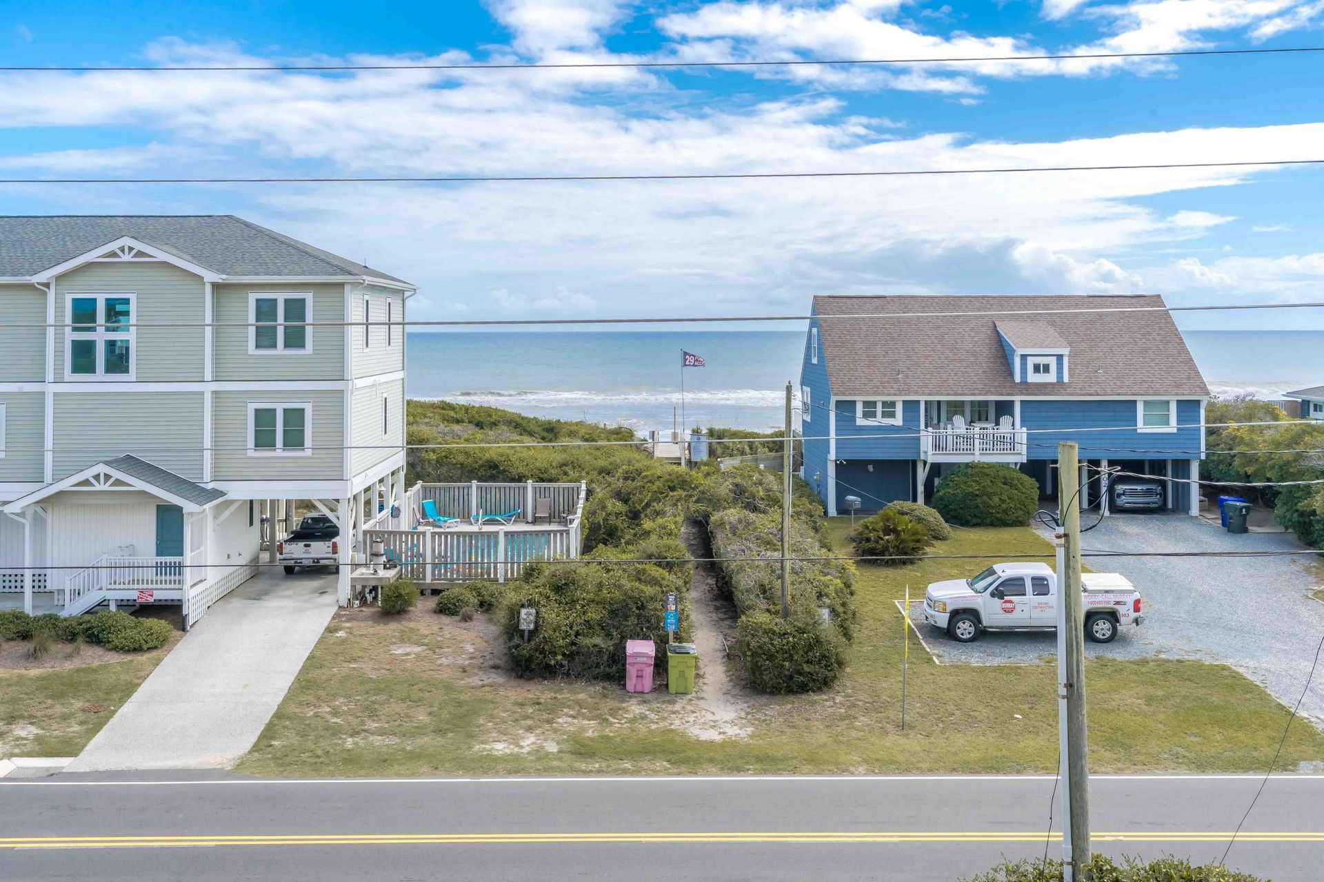 A coastal residential area with two houses, a dock, and a beach view.