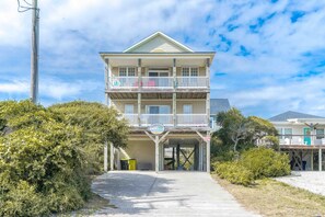A multi-story building with a covered entrance and a parking area. - Seas The Moment - 2nd Row, 4 BR Home with Covered Porches (Surf City)