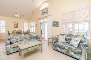 A spacious living room with two sofas, a coffee table, and a dining area with chairs and a table.