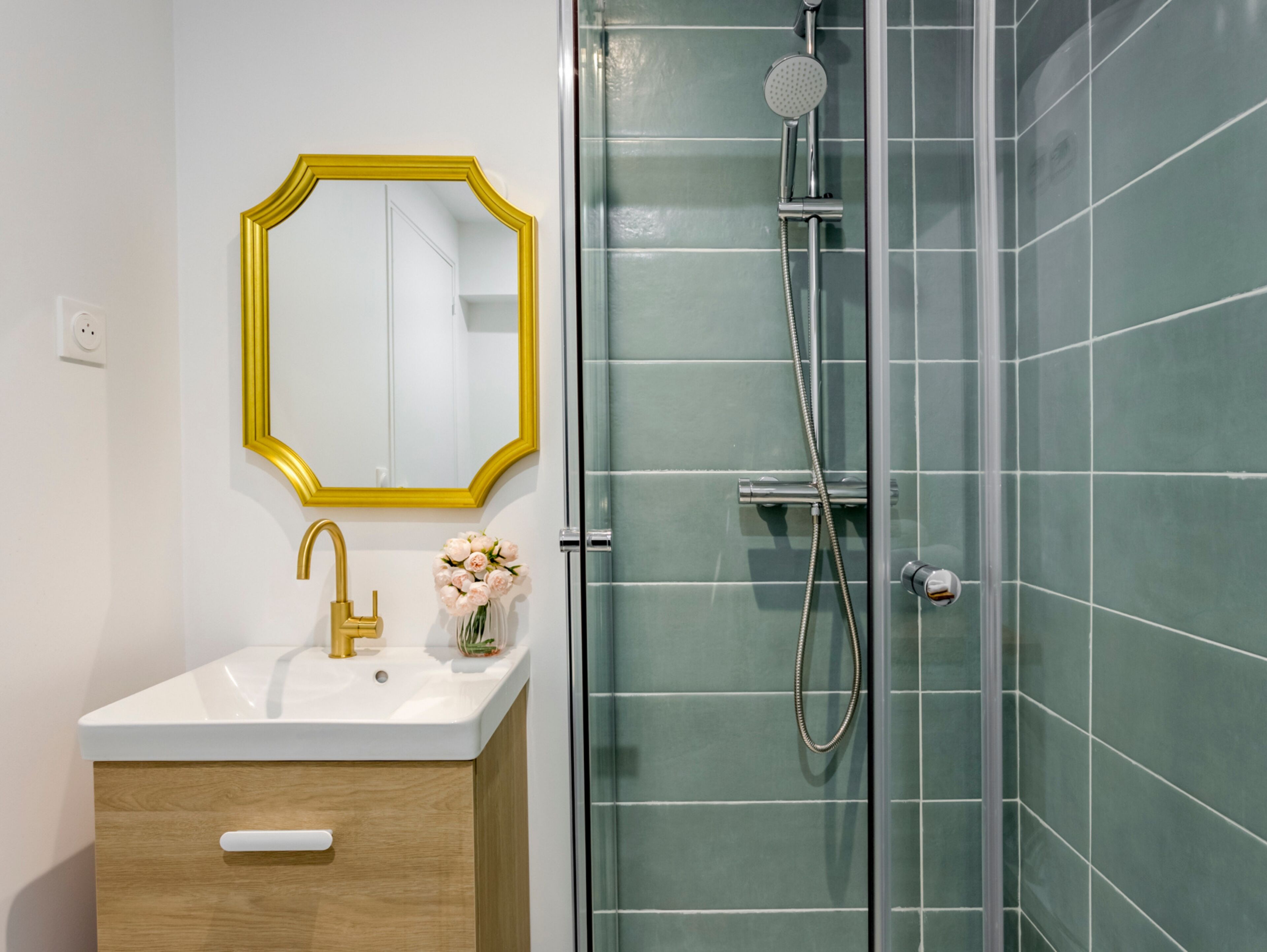A bathroom with a white sink, gold faucet, and a mirror with a gold frame.