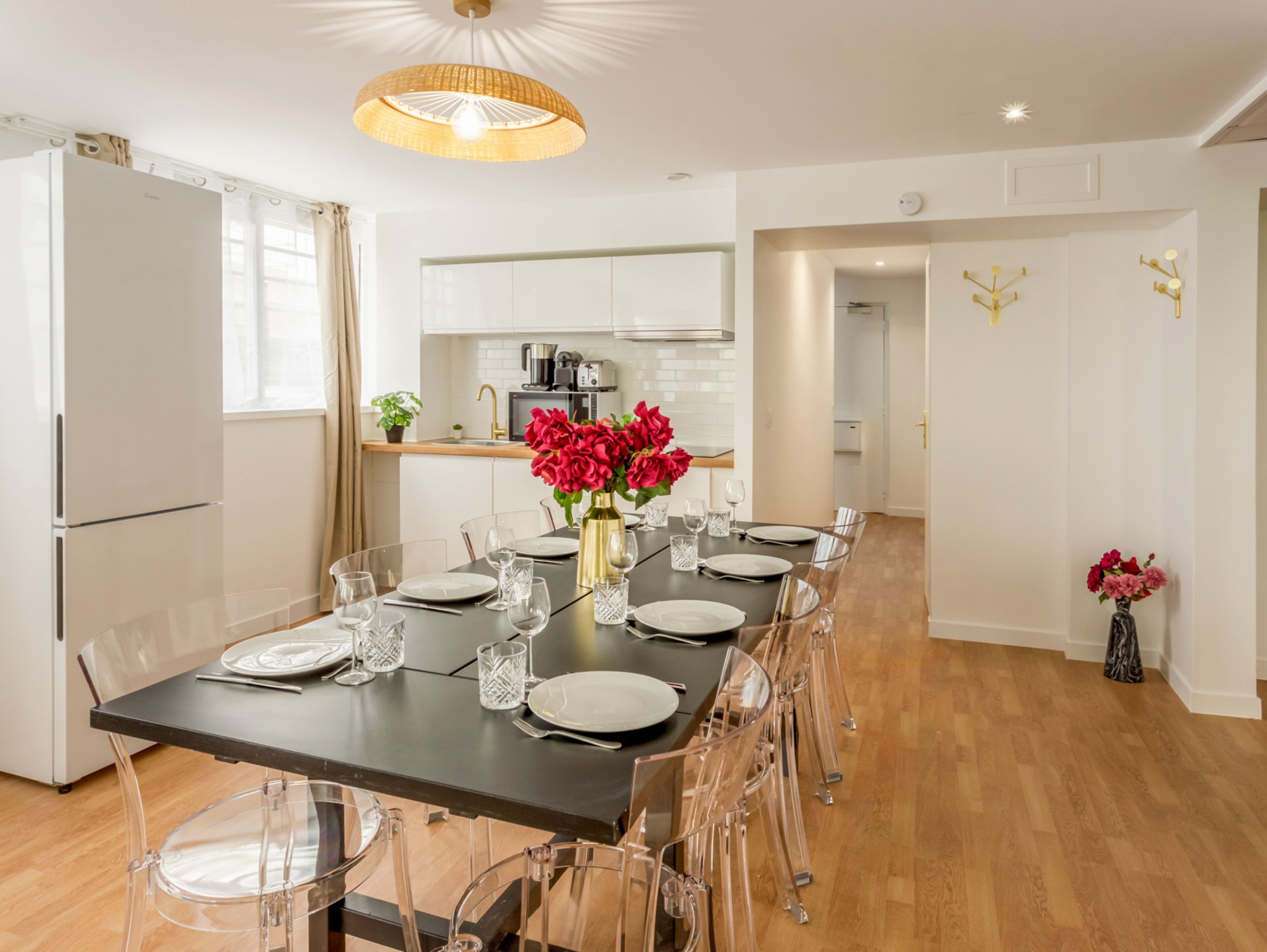 Een moderne keuken met witte kasten, een eettafel gedekt voor zes personen en een kroonluchter.