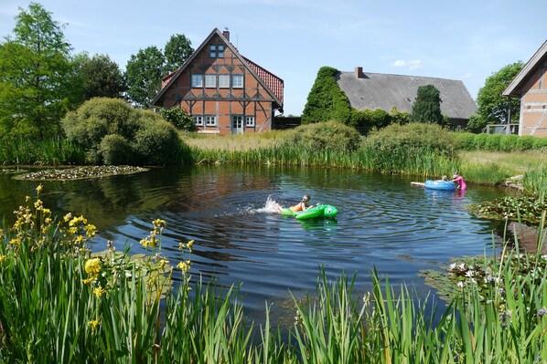A calm river with a house and greenery in the background.