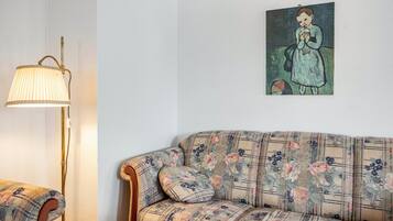 Een kamer met een bank, een lamp en een schilderij aan de muur.