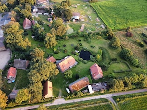 An aerial view of a residential area with houses, a pond, and surrounding greenery.