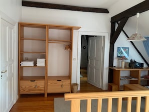 A wooden wardrobe with shelves and drawers, a small table with a lamp, and a staircase with a wooden railing. - Apartment "Swallow's Nest" with Shared Garden and Wi-Fi (Trebel)