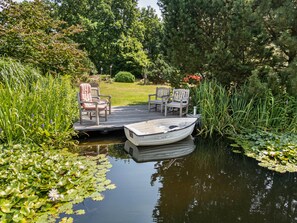 A serene outdoor deck with a boat docked, surrounded by lush greenery and water lilies. - Apartment "Swallow's Nest" with Shared Garden and Wi-Fi (Trebel)