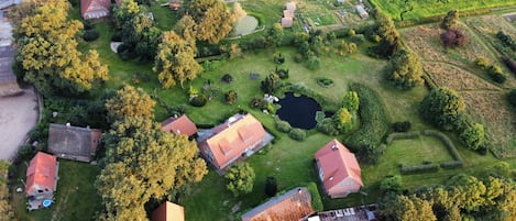 Ett flygbildsfoto av ett bostadsområde med hus, en damm och omgivande grönska.