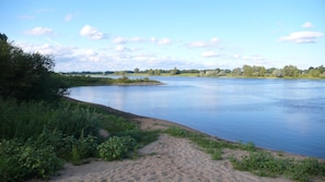 Ein Fluss mit sandigem Ufer und viel Grün.