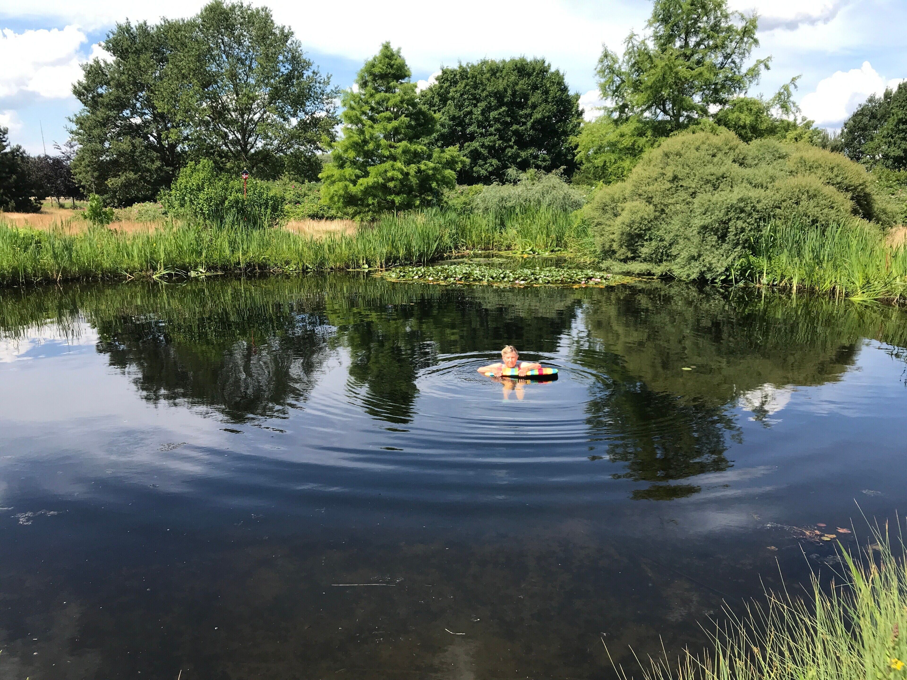 Une étendue d’eau calme, sur laquelle flotte une personne allongée sur une bouée colorée.