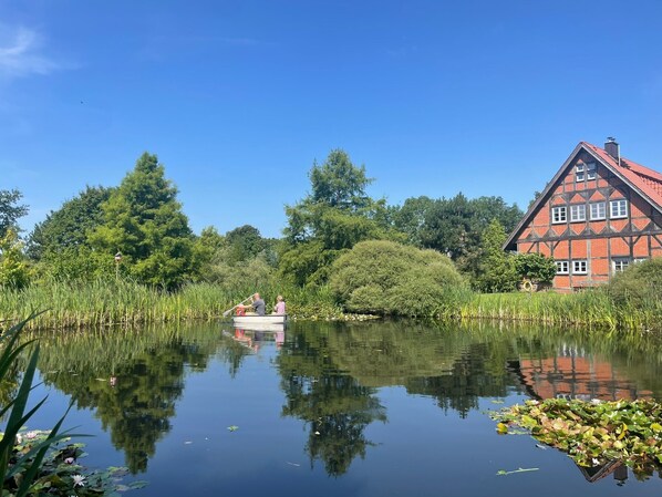 A calm lake with a house and trees in the background.