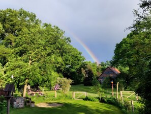 A lush garden with a rainbow, a wooden fence, and a house in the background. - Holiday Home 'Historisches Uhlenhorst' with Private Terrace, Garden and Wi-Fi (Trebel)