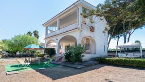 A two-story building with a covered patio area, outdoor seating, and a staircase leading to the upper level.