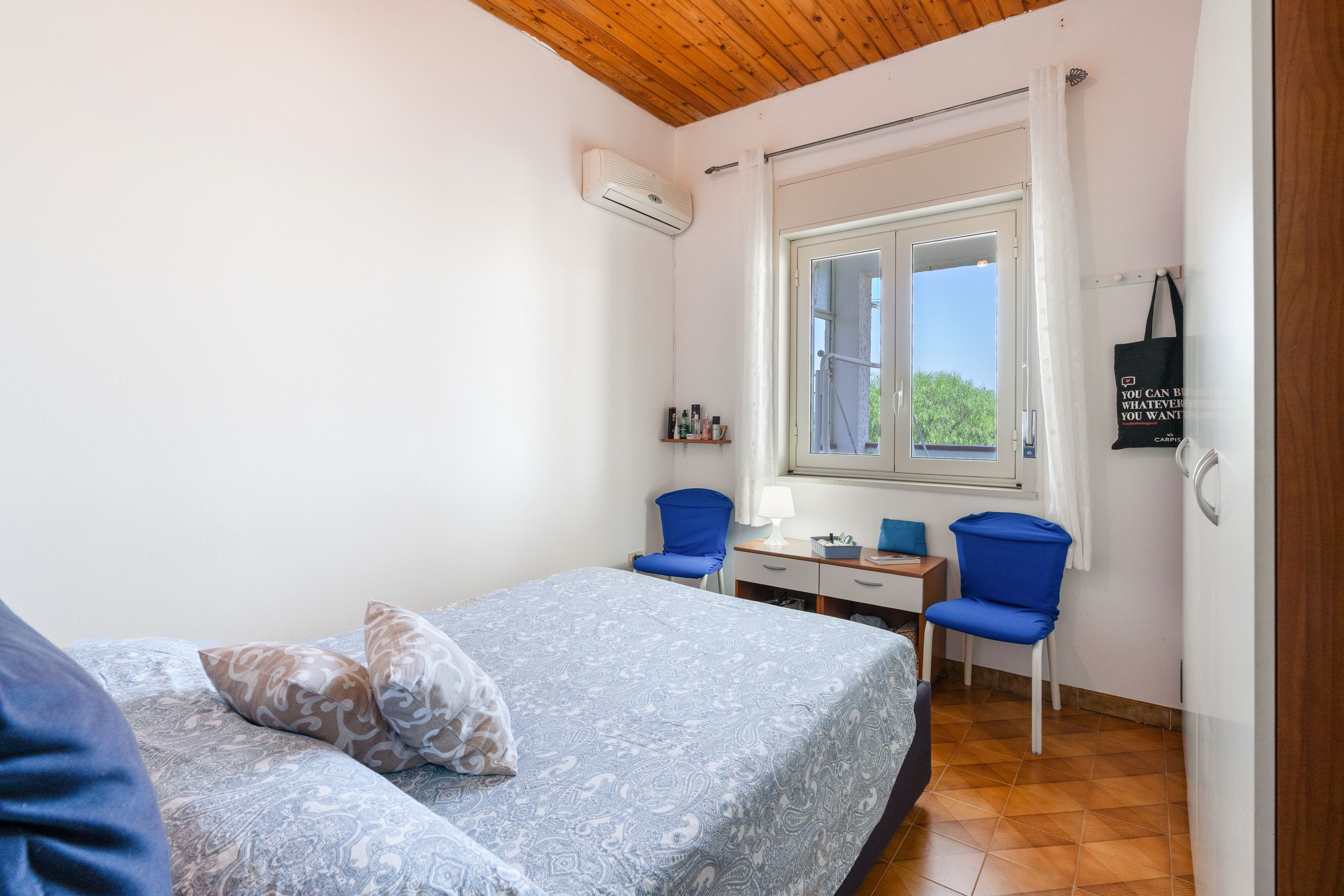 Ein Schlafzimmer mit einem Bett, zwei Stühlen, einem Schreibtisch und einem Fenster.