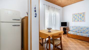 Ein kompakter Wohnbereich mit Küchenzeile, einer Essecke mit Tisch und Stühlen, einer Sitzecke und einem Fernseher.
