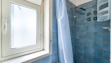 Une salle de bain avec une douche, des toilettes et une fenêtre.