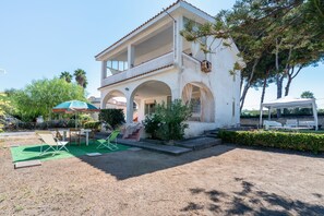 A two-story building with a covered patio area, outdoor seating, and a staircase leading to the upper level. - Casa Orchidea with Veranda – Private Terrace, Wi-Fi & Air Conditioning (Costa Saracena - Castelluccio)