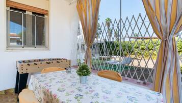 Ein Zimmer mit gedecktem Tisch für zwei Personen, einem Fenster mit Jalousien, einem Holz-Kopfteil und Blick auf einen Pool und Grünflächen.