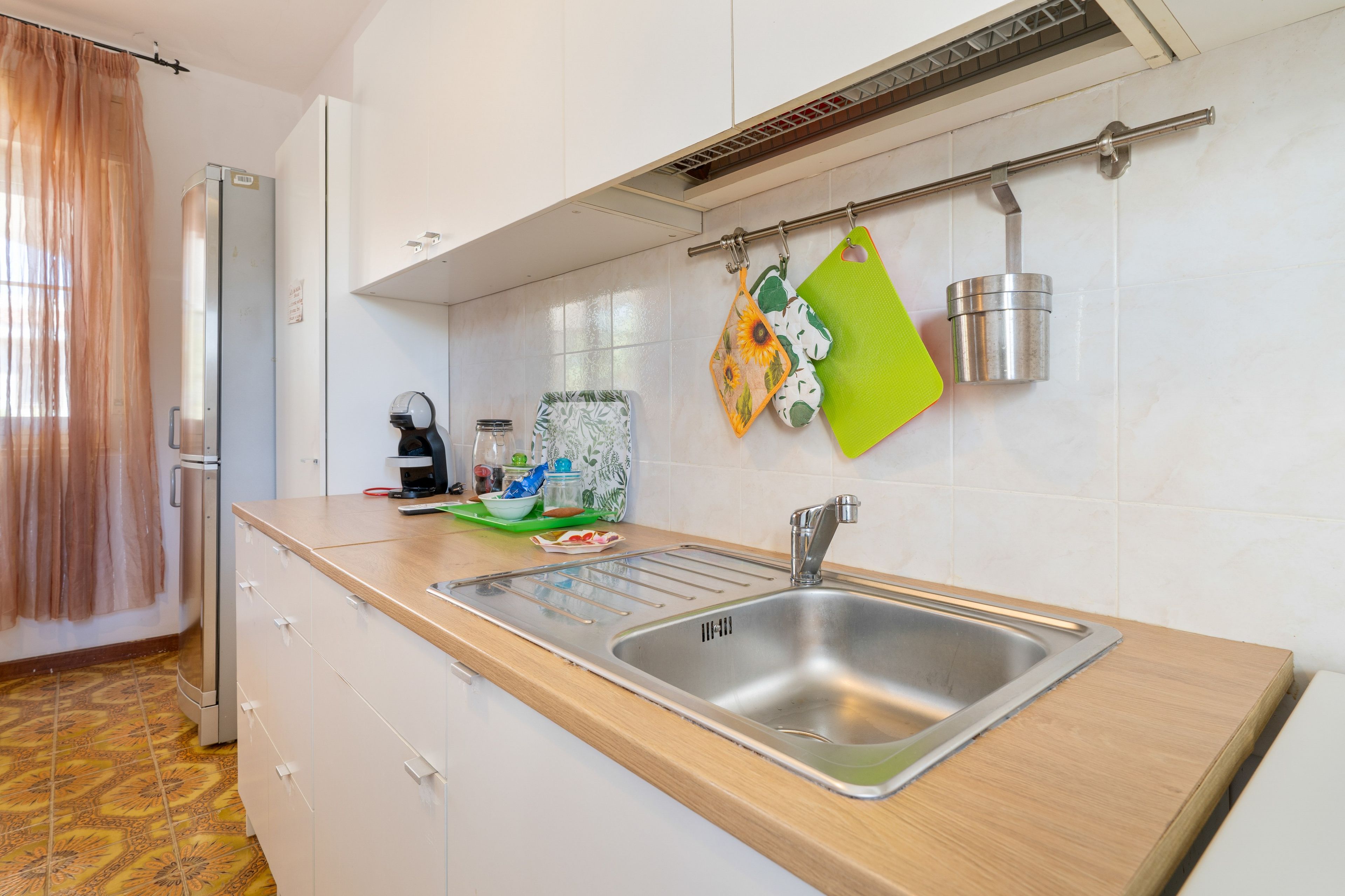 Eine moderne Küche mit Spüle aus Edelstahl, einer Mikrowelle und einem Wasserkocher auf der Arbeitsfläche.