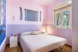 A bedroom with a bed, bedside table, lamp, and a window with curtains. - Casa Orchidea with Veranda – Private Terrace, Wi-Fi & Air Conditioning (Costa Saracena - Castelluccio)