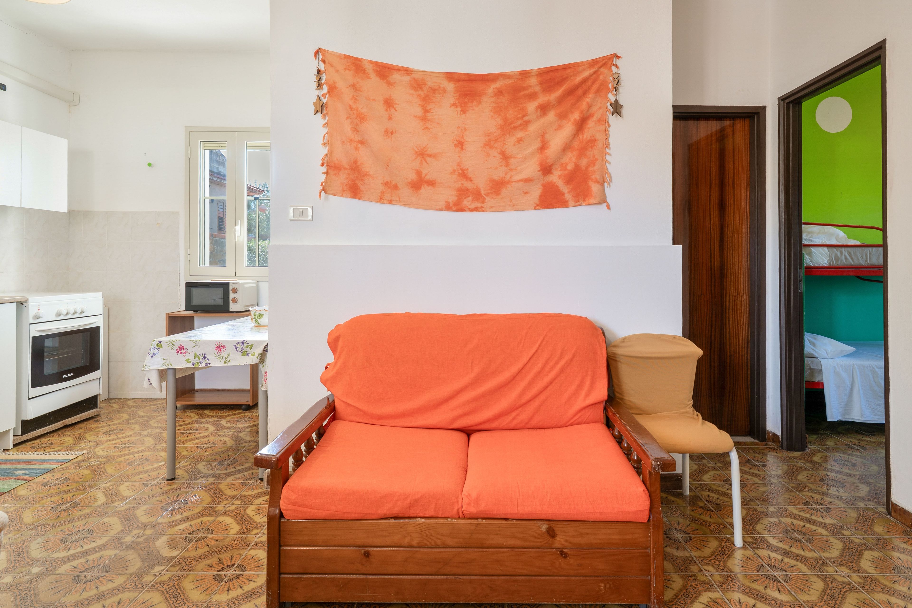 Ein kompakter Wohnbereich mit einer Couch, einem kleinen Tisch, einer Küchenzeile und einem Bett im angrenzenden Zimmer.