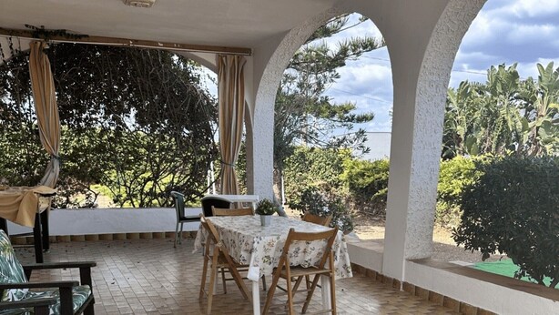 An outdoor patio with a checkered floor, a table with chairs, and a sofa. - Casa Orchidea with Veranda – Private Terrace, Wi-Fi & Air Conditioning (Costa Saracena - Castelluccio)