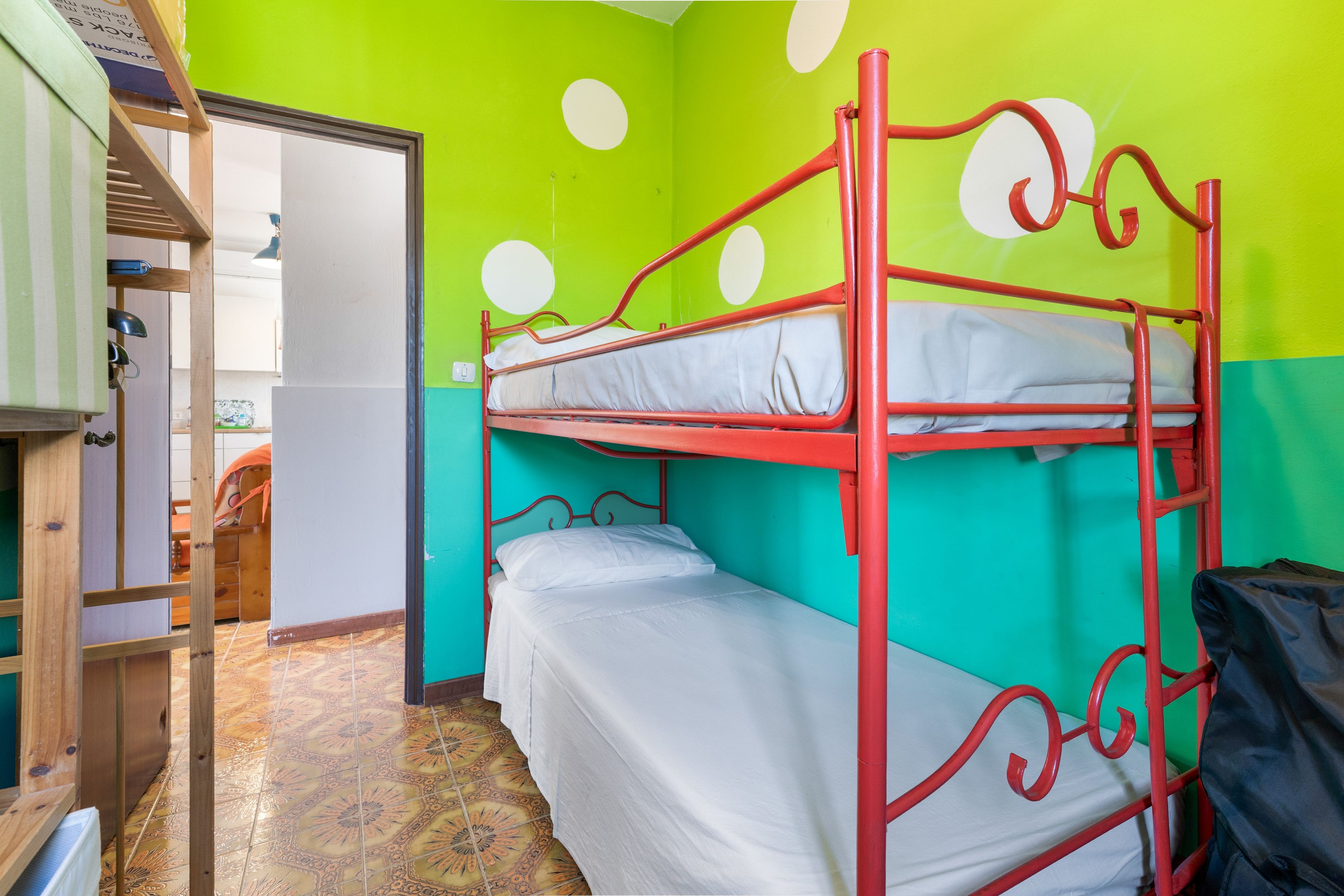 Una camera con letti a castello, una parete verde e un pavimento decorato.