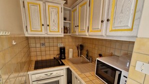 A compact kitchen with white cabinets, a black stove, a microwave, and a sink. - Apartment for 4 near slopes and activities (Besse-et-Saint-Anastaise-Super Besse)