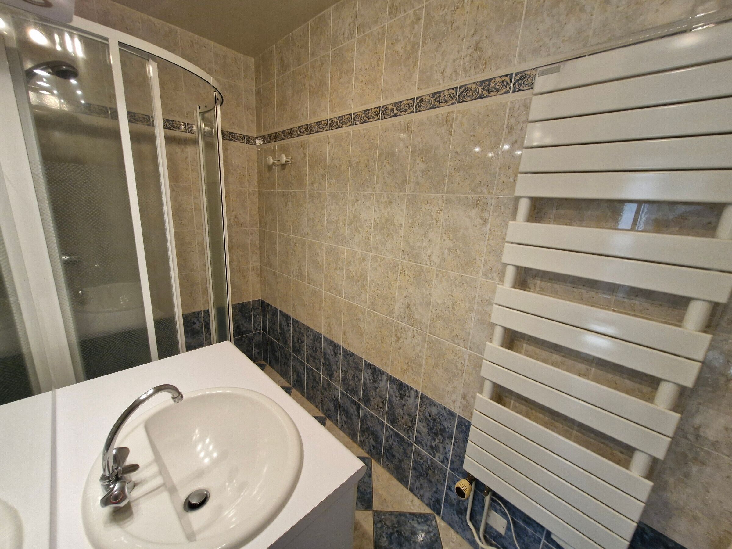 Un bagno con un lavandino bianco, una cabina doccia in vetro e un porta asciugamani.