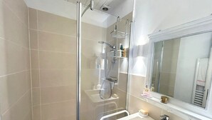 Une salle de bain moderne avec une douche à parois de verre, un lavabo avec un miroir et un porte-serviettes.