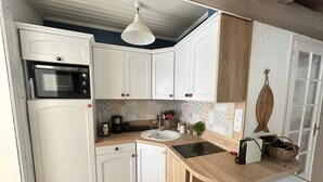 Une cuisine de taille réduite avec des meubles blancs, une cuisinière noire, un évier et un plan de travail en bois.