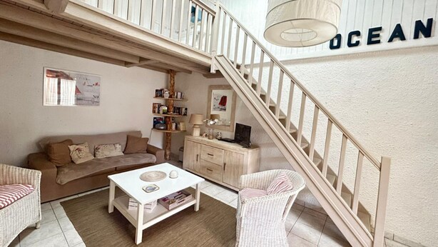 Un vaste espace de vie doté d’un haut plafond, d’un escalier et d’une grande fenêtre.