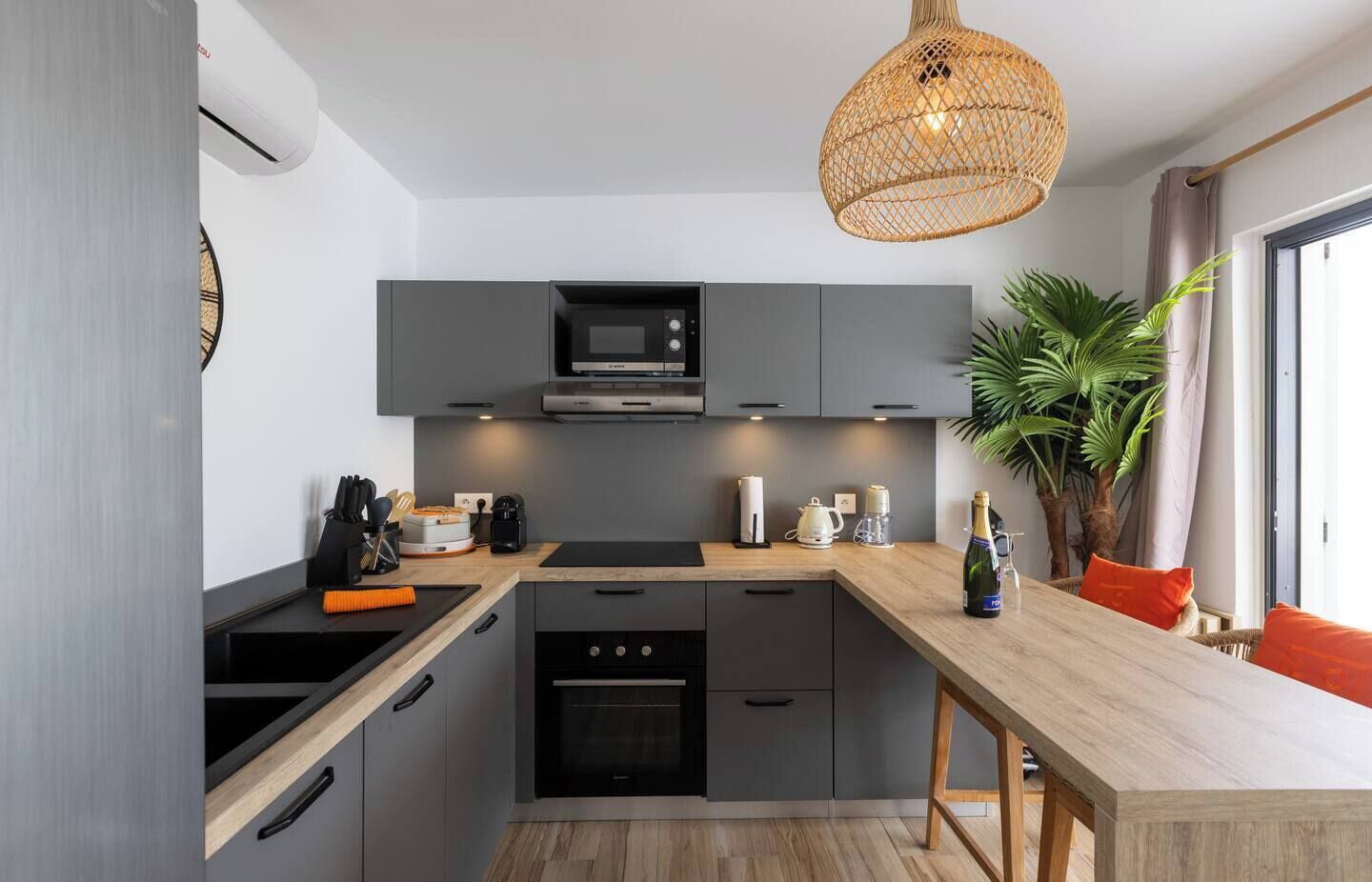 A modern kitchen with grey cabinets, a built-in oven, and a wooden countertop.