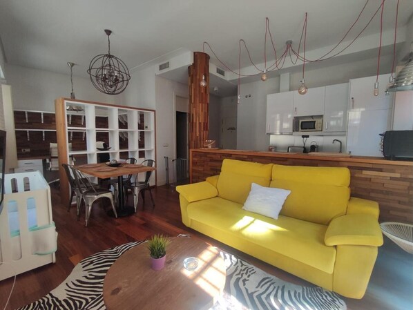 A modern living room with a yellow sofa, wooden dining table, and a zebra-patterned rug.