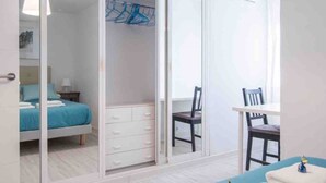 A bedroom with a bed, a desk, a chair, and a wardrobe with a mirror. - Comfortable apartment near Seville city center (Sevilla)
