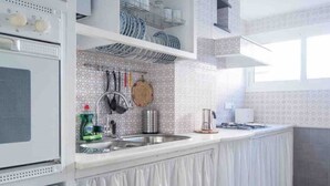 A modern kitchen with white cabinetry, a built-in oven, and a stainless steel sink. - Comfortable apartment near Seville city center (Sevilla)