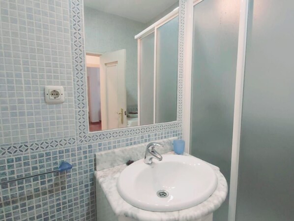 A bathroom with a white sink, a mirror, and patterned tiles.
