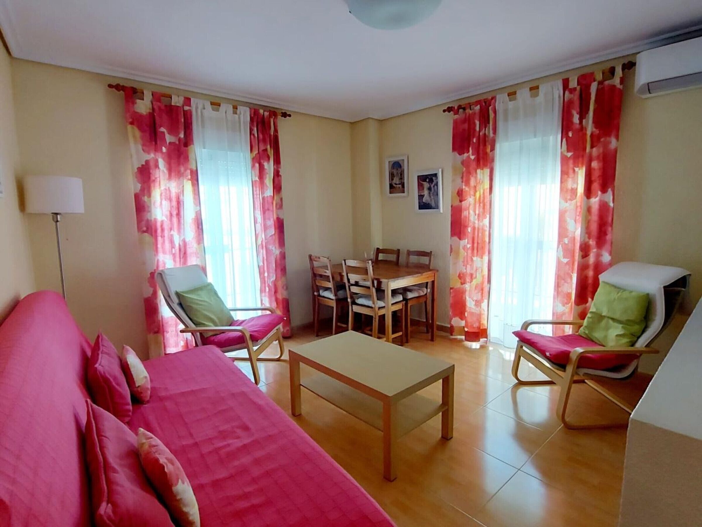Une pièce comprenant un lit, deux fauteuils, une table à manger et des rideaux.