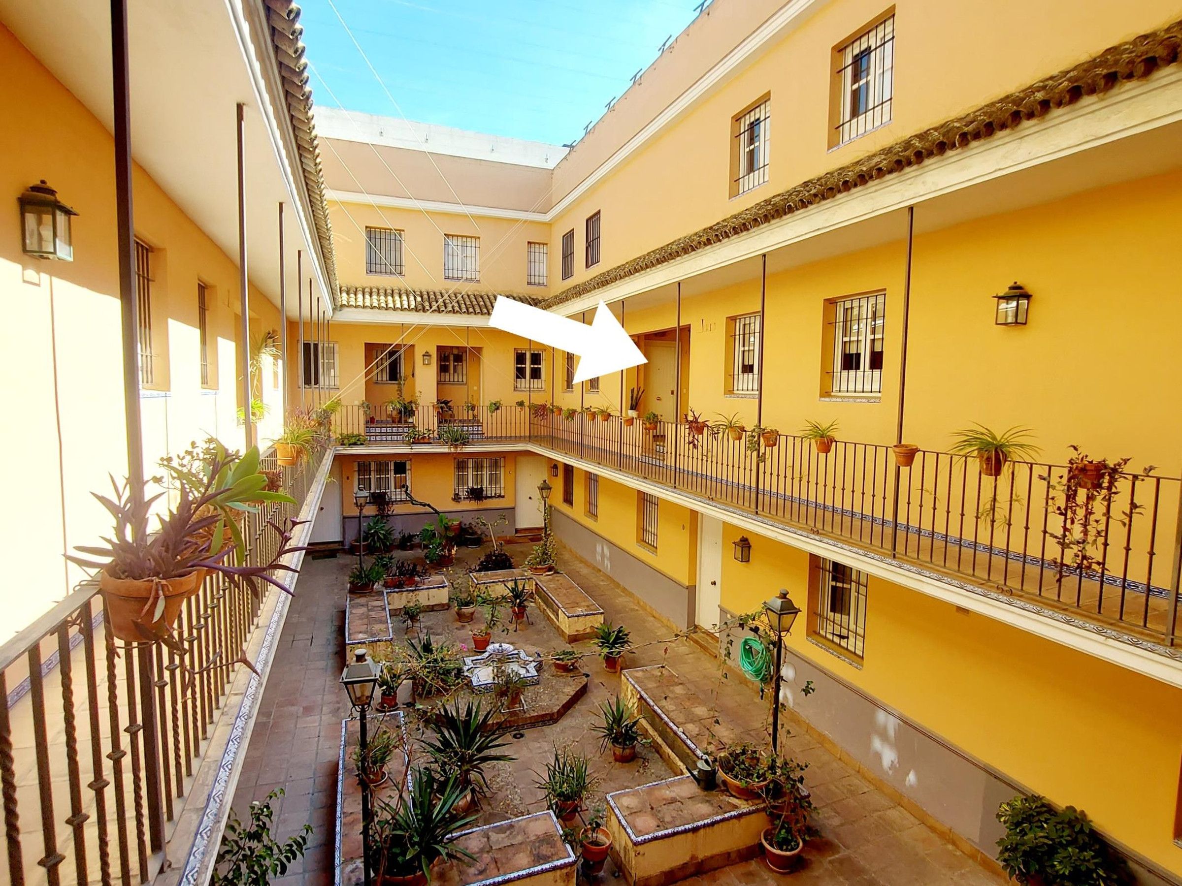A courtyard with multiple balconies, potted plants, and a central seating area.