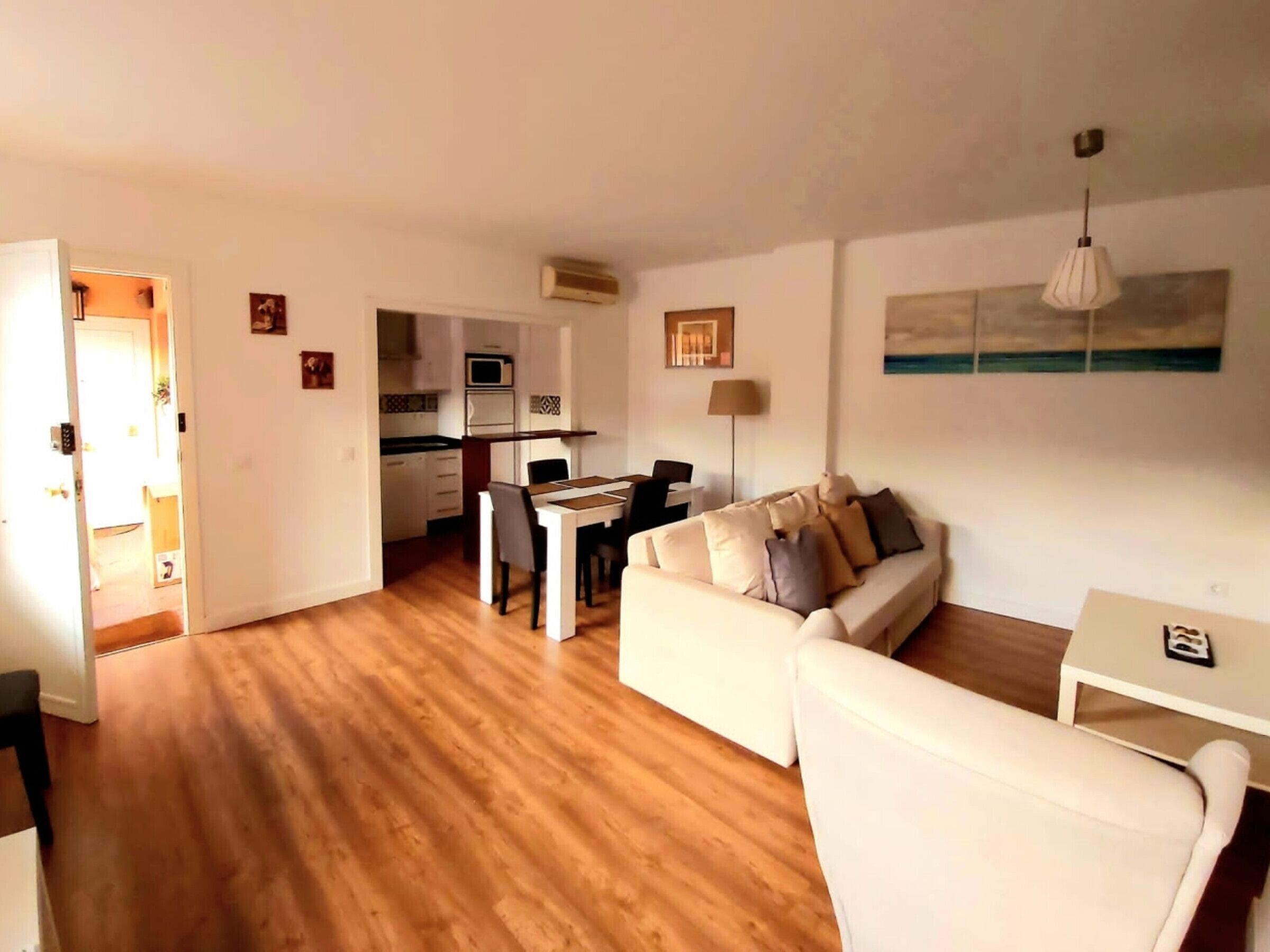 Una sala de estar con sofá, una mesa de comedor y una cocina al fondo.