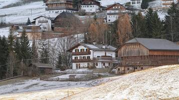 A cluster of traditional wooden buildings with balconies, situated on a hillside with snow-covered ground.