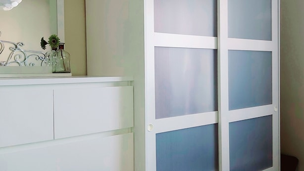Une salle de bain avec un meuble-lavabo blanc, un miroir et une porte en verre dépoli.
