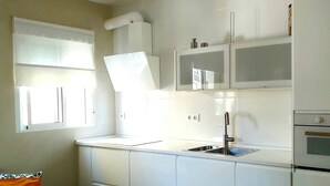 Une cuisine de taille réduite avec des meubles blancs, un évier et une fenêtre.